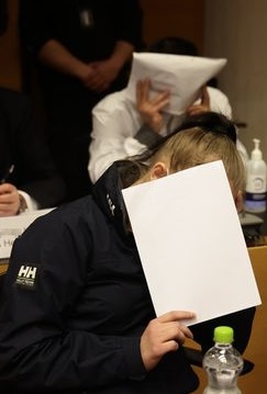 MC Apache -rikoskokonaisuuden syytetyt istuivat oikeudenkäyntiavustajiensa vieressä ja peittelivät kasvojaan kuvaajilta. MATTI MATIKAINEN/Iltalehti.