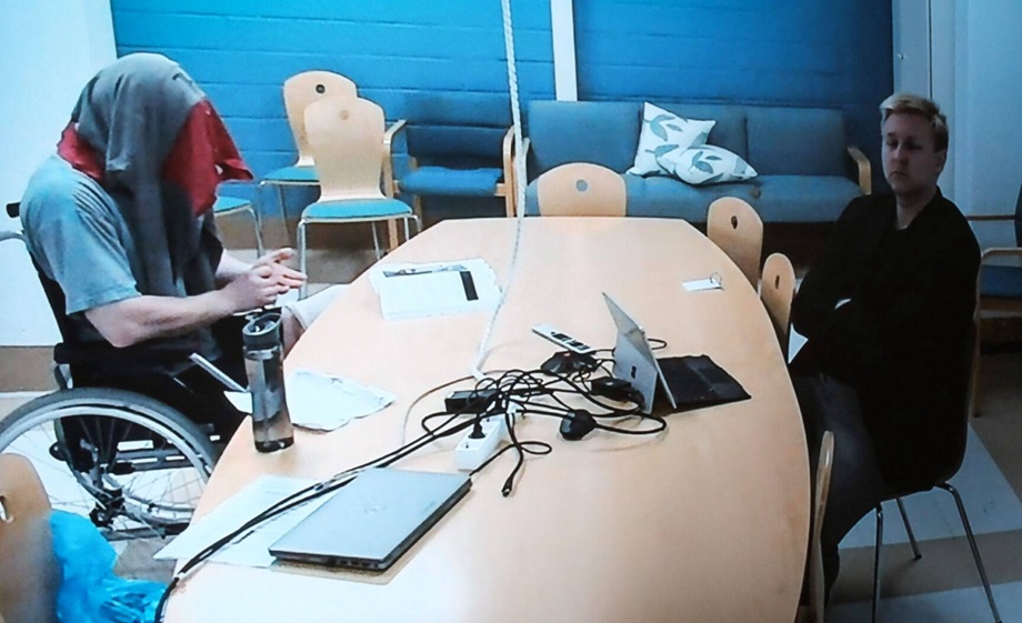 Murhasta ja törkeästä ryöstöstä syytetty mies osallistui oikeudenkäyntiin etäyhteydellä. Kuvaushetken ajaksi hän peitti kasvonsa vaatteella. Oikealla puolustusasianajaja Teemu Kemppi. KUVA: JOOSUA LEHTINEN