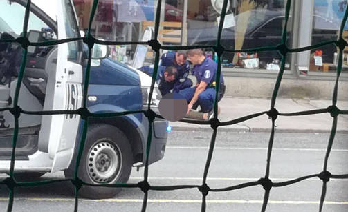 Ihmiset potkivat ja löivät puukottajaa päähän ja ylävartaloon. Kuvassa poliisit ovat kerääntyneet epäillyn ympärille. (LUKIJAN KUVA). Tekijän hipiää samennettu, ettei tule paha mieli. Hänelle eikä itseään toimittajaksi kutsuvallle Rebekka Härköselle.