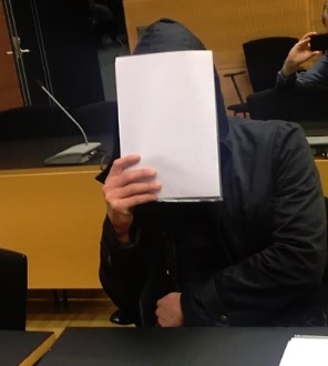 Tapon yrityksestä syytetty parrakas ja kauluspaitaan pukeutunut mies peitti kasvonsa oikeudessa hupparilla ja paperinipulla.