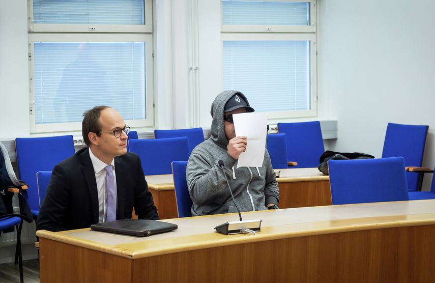 Syytteessä oleva mies piilotui paperiarkin taakse valokuvaajien kuvatessa häntä oikeussalissa.